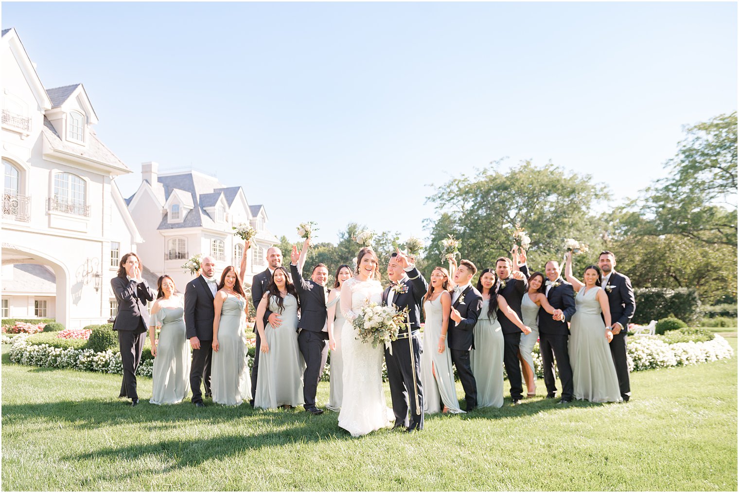 newlyweds stand on lawn by Park Chateau Estate with bridal party in navy and sage green 