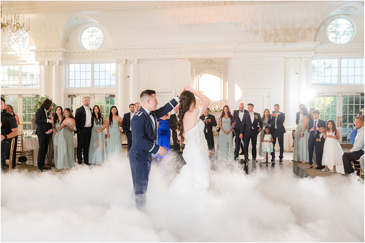 groom twirls bride during first dance with fog around them
