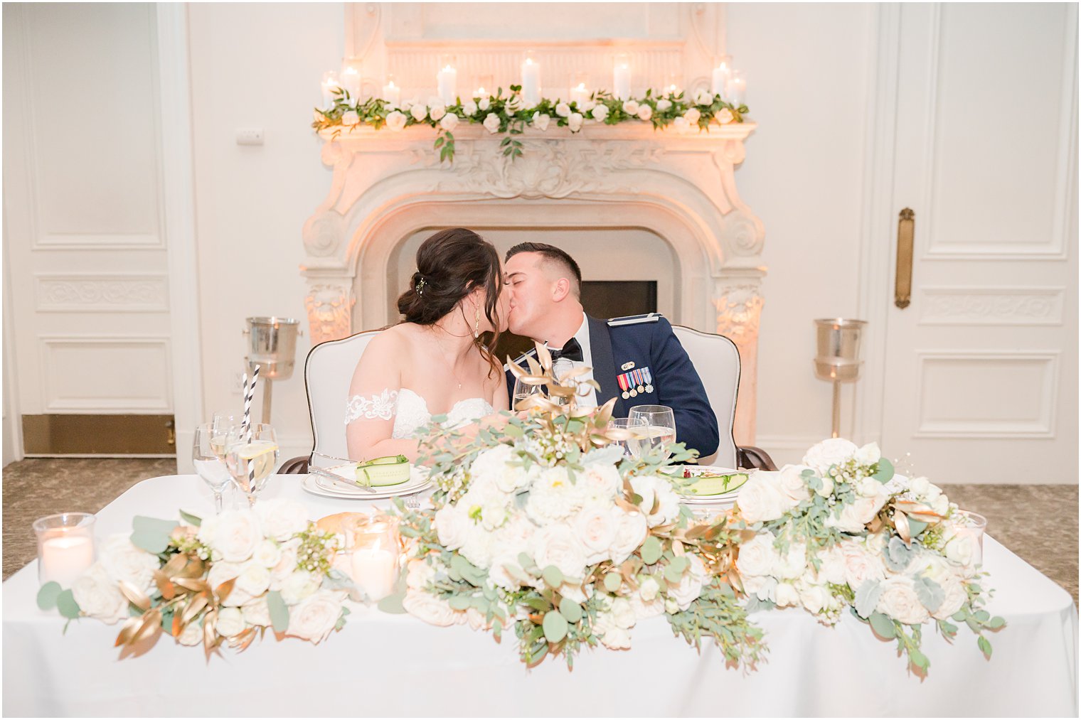 bride and groom kiss at sweetheart table with ivory flowers 