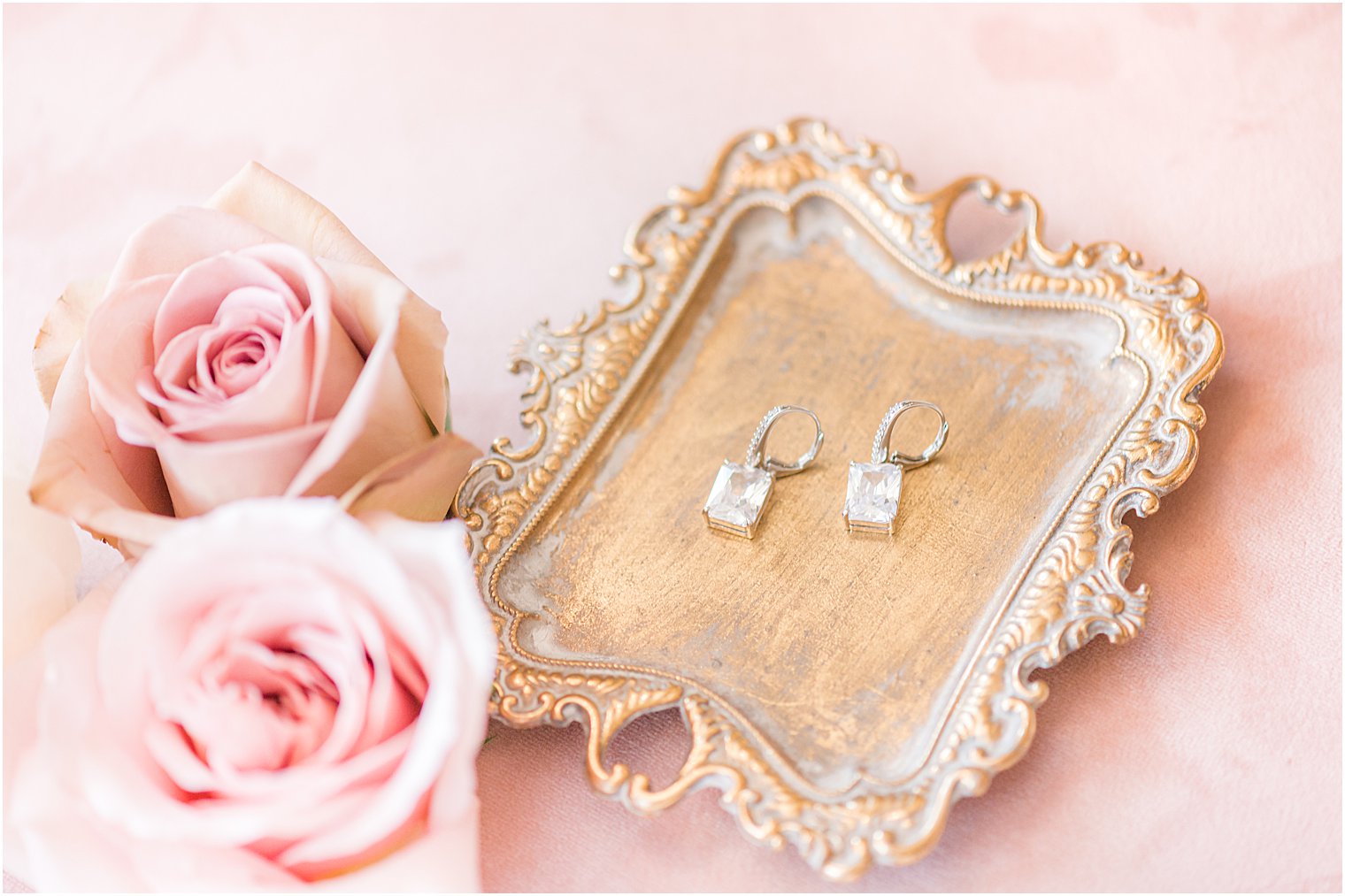 bride's jewelry lays on gold tray with pink roses