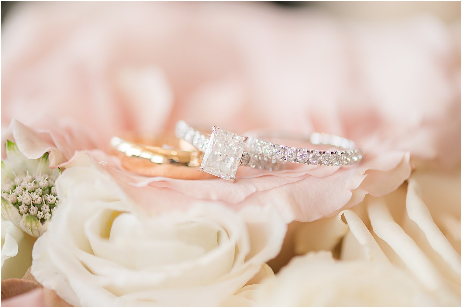 silver wedding band lays on pink and white roses 