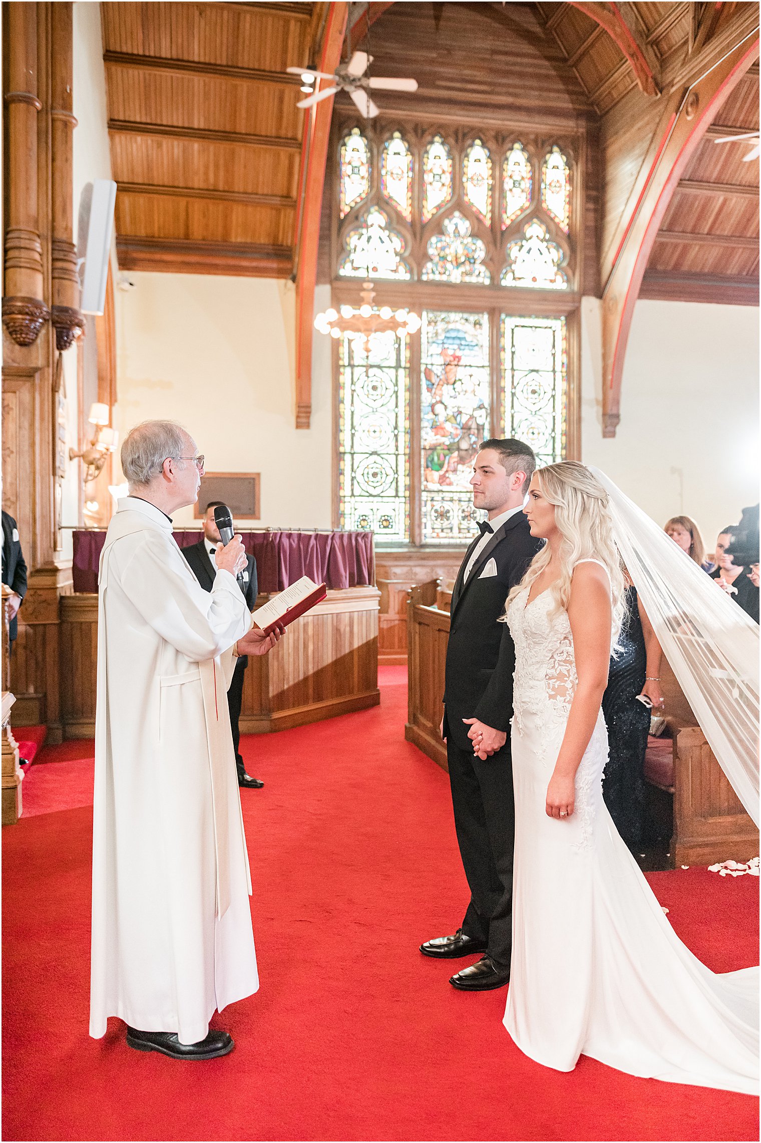 bride and groom stand together with officiant during traditional church wedding in New Jersey