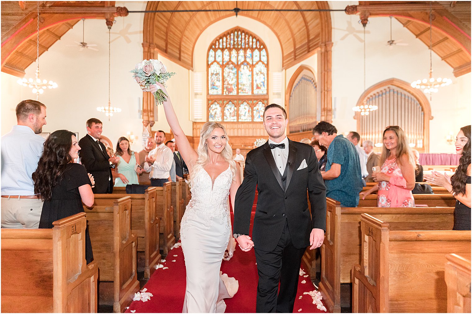 newlyweds cheer walking up aisle after traditional church wedding in New Jersey