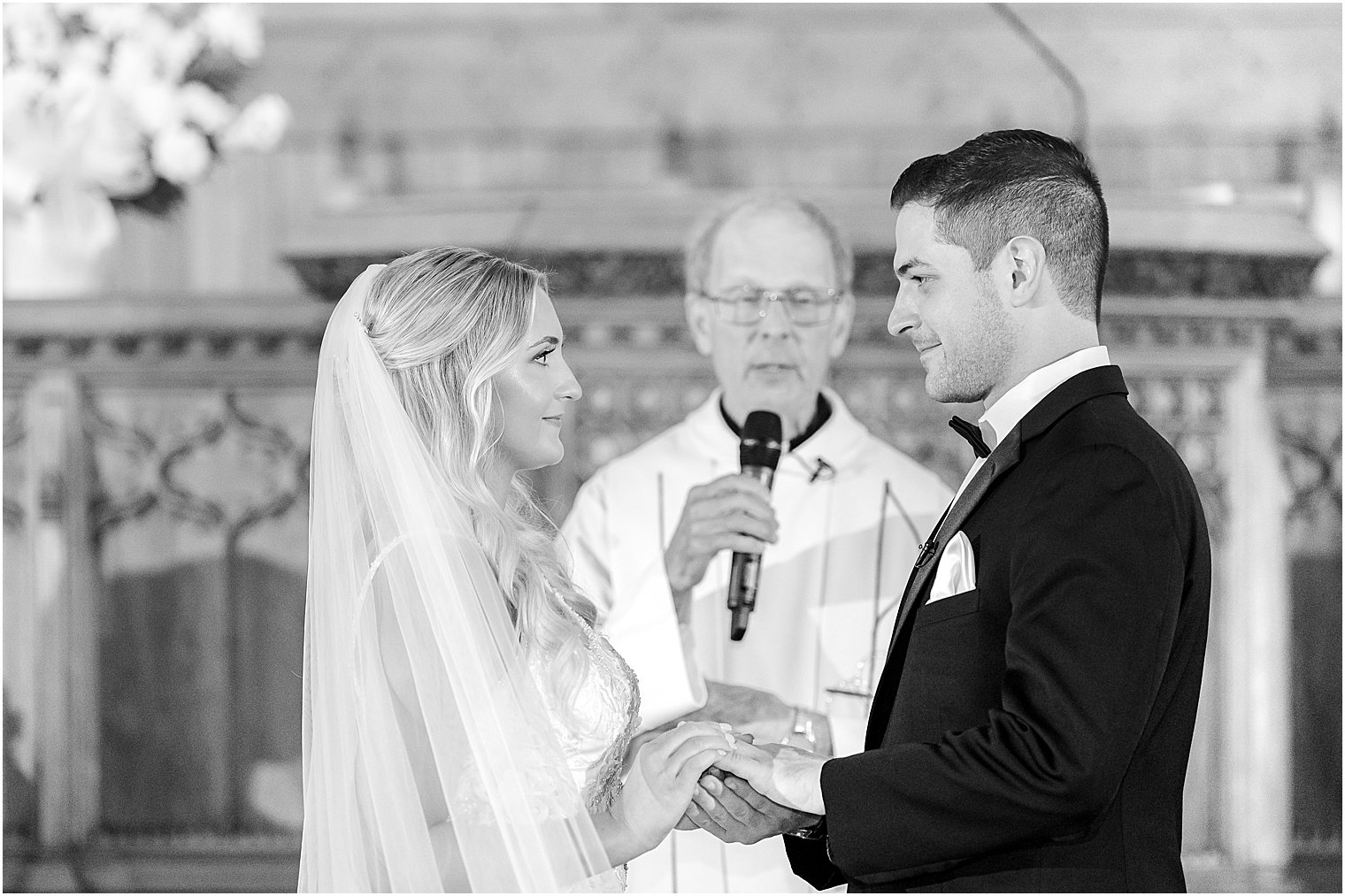 newlyweds hold hands during vow exchange in traditional church wedding in New Jersey