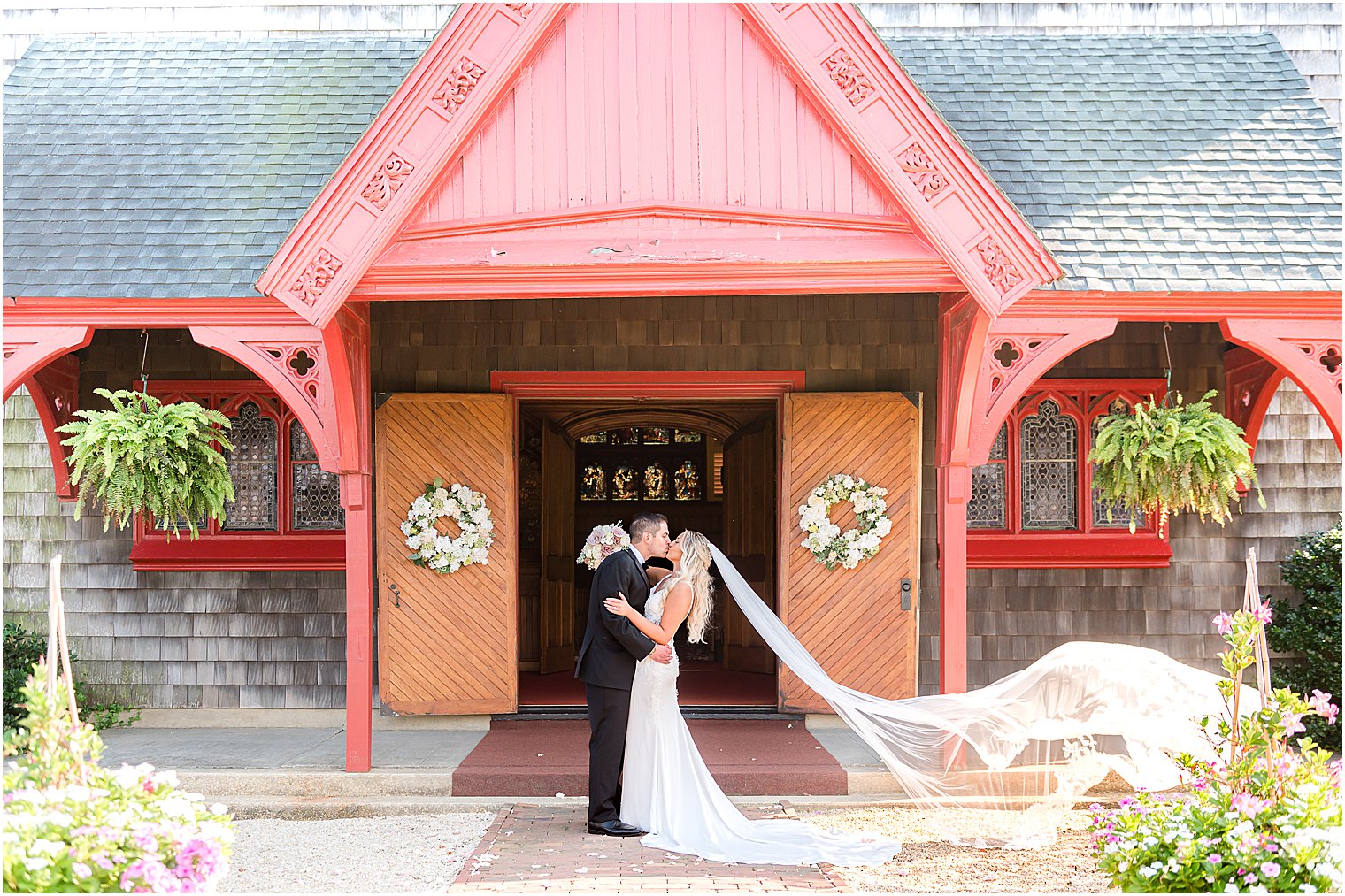 bride and groom kiss by wooden doors outside church in New Jersey