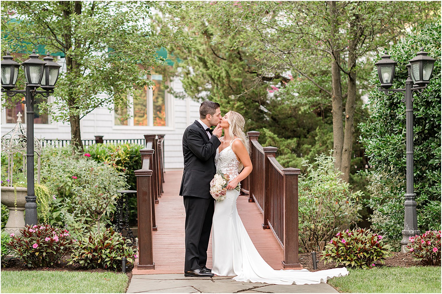 bride and groom kiss by wooden bridge at The English Manor