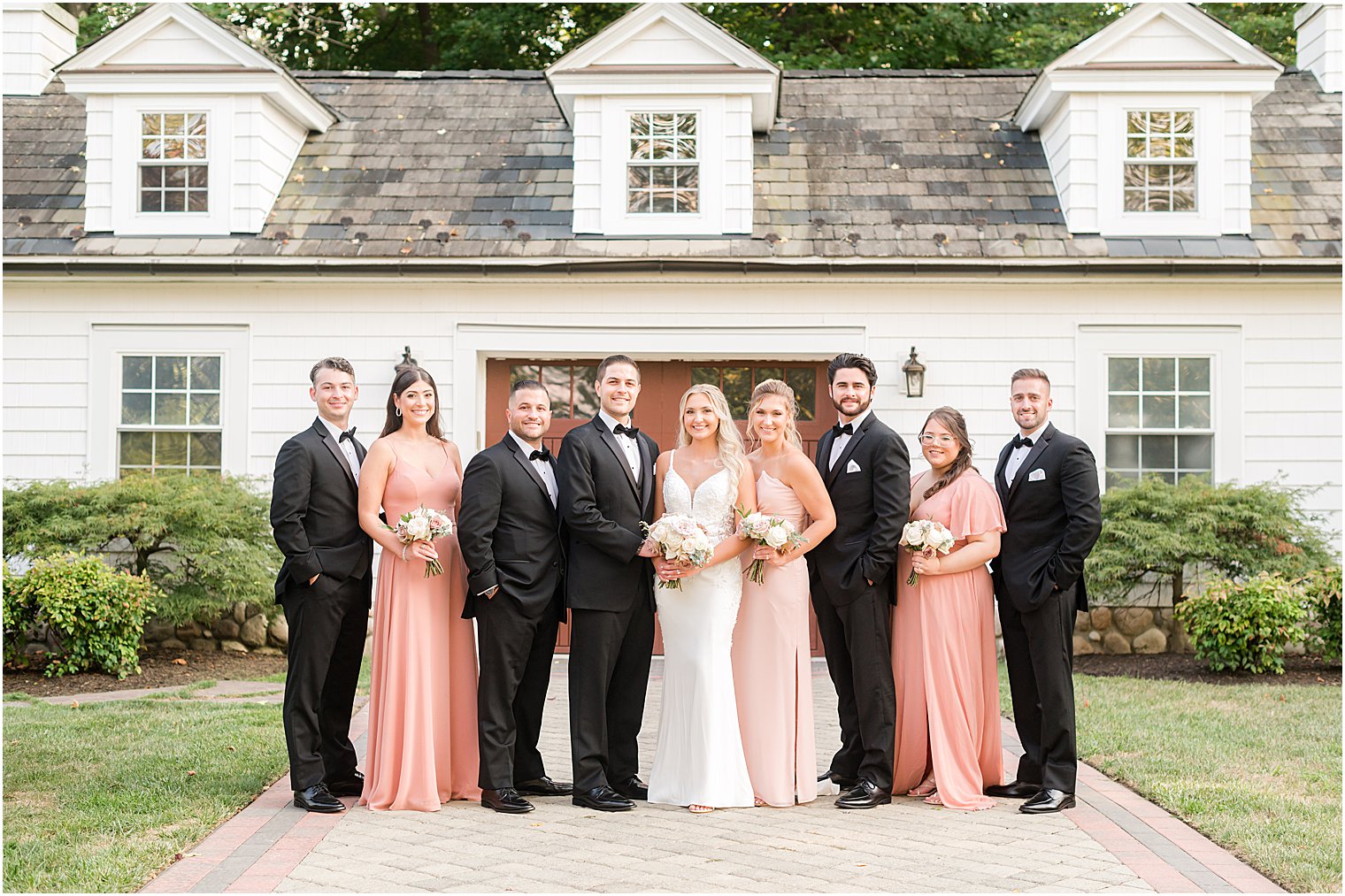 newlyweds pose with wedding party in pink and black attire