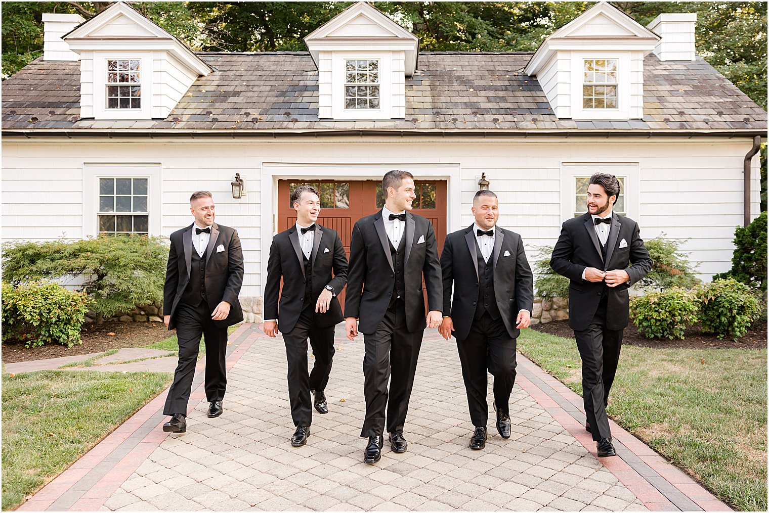 groom walks with groomsmen in black suits at The English Manor