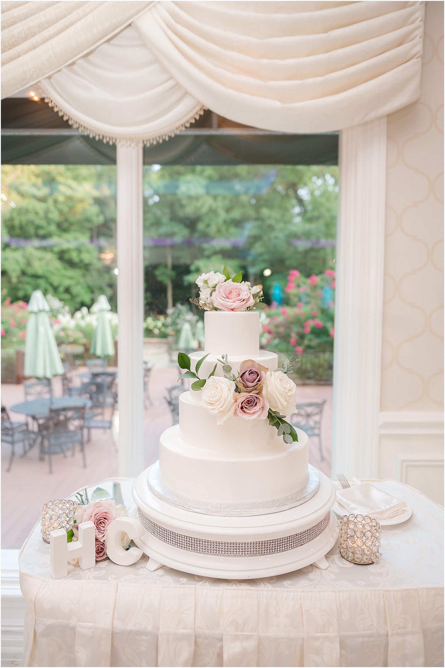 tiered wedding cake sits by window in ballroom at The English Manor