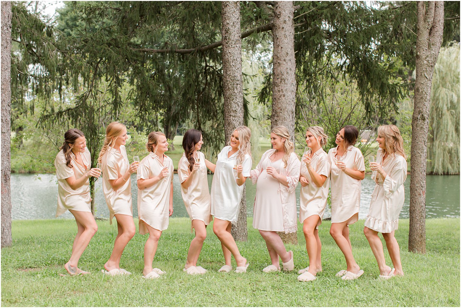 bride and bridesmaids laugh in matching robes on lawn at Windows on the Water at Frogbridge