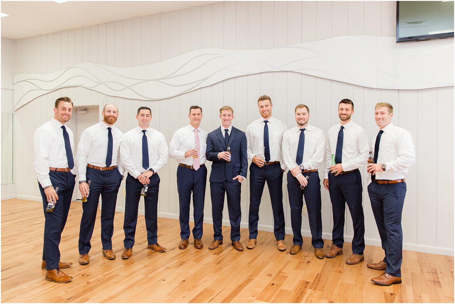 groom stands with groomsmen in suite at Windows on the Water at Frogbridge