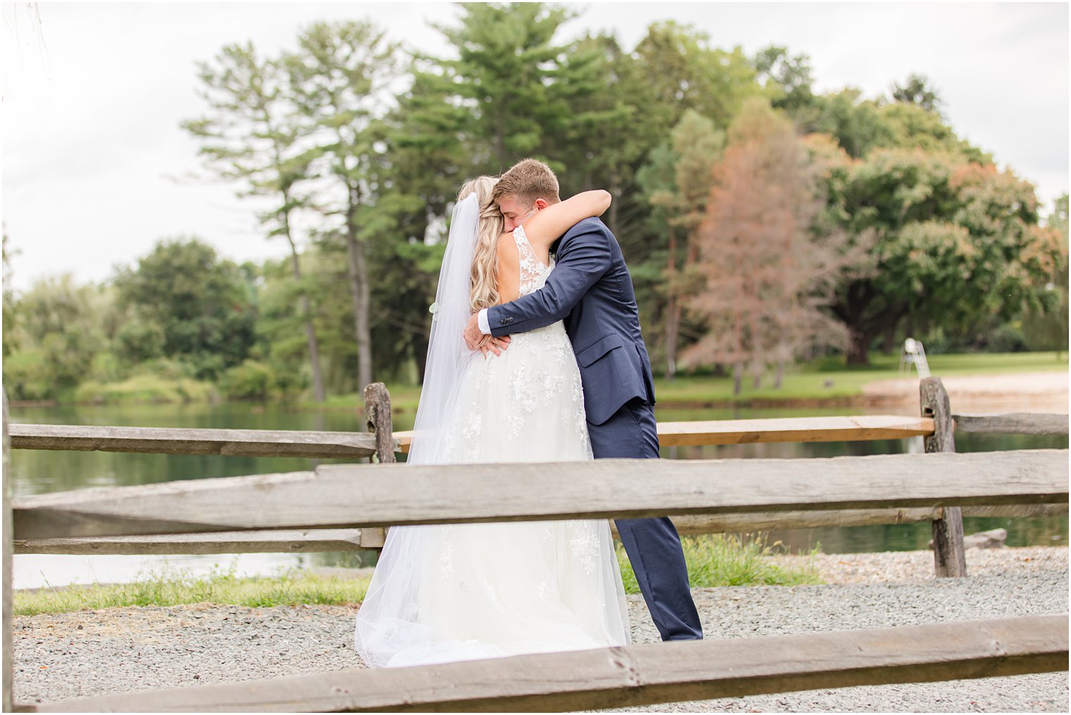 bride and groom hug along fence line at Windows on the Water at Frogbridge
