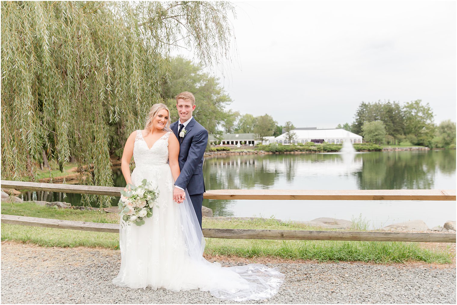 newlyweds stand with tent at Windows on the Water at Frogbridge behind them 