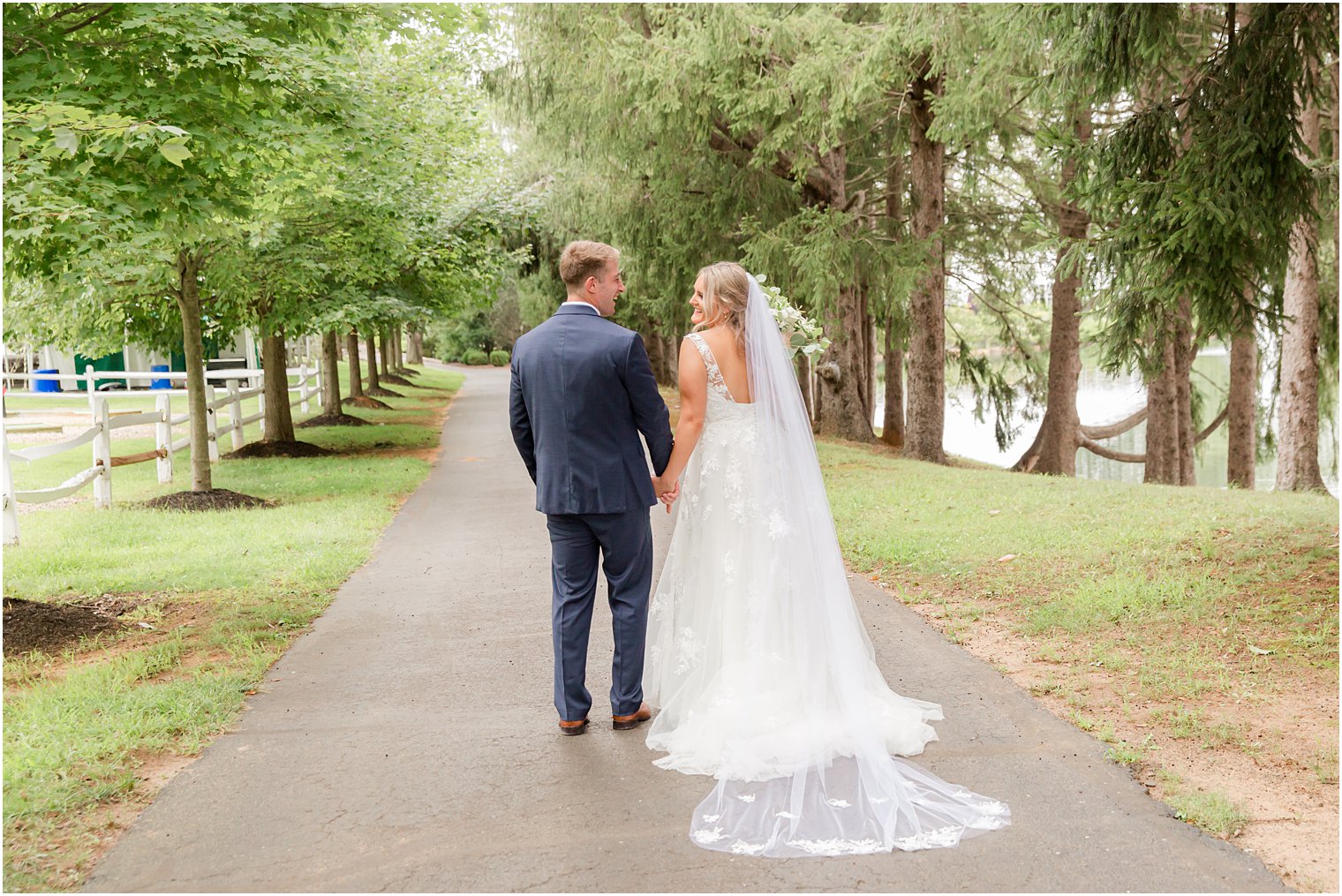 bride and groom hold hands walking down driveway at Windows on the Water at Frogbridge