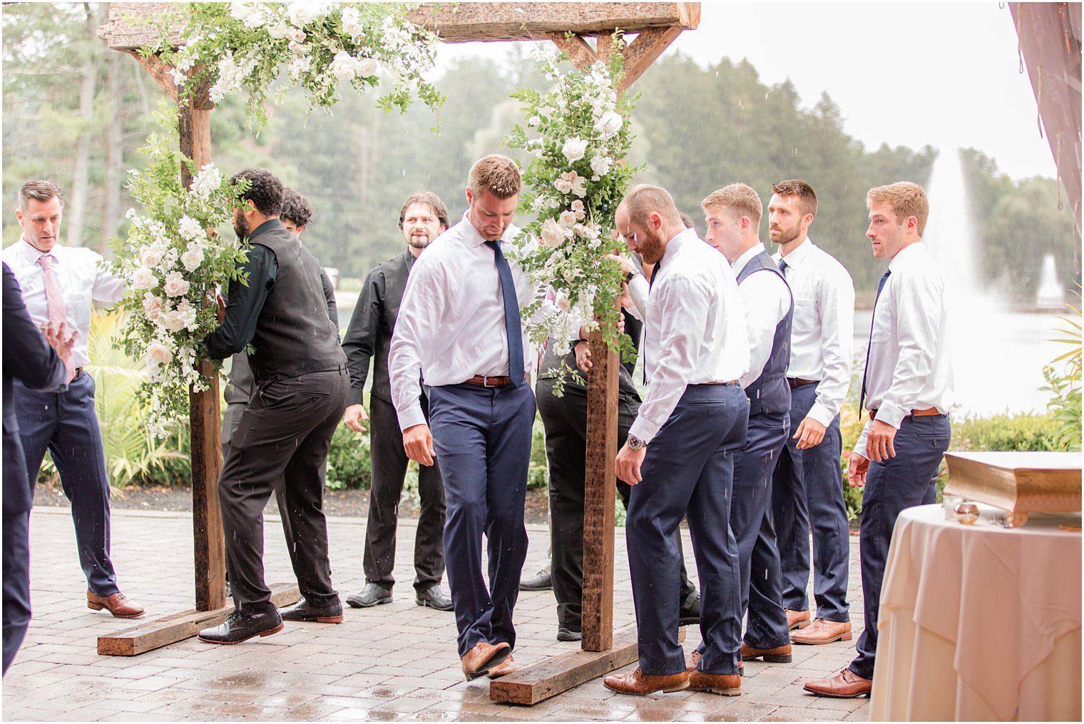 vendors and groomsmen move wooden arbor under tent at Windows on the Water at Frogbridge