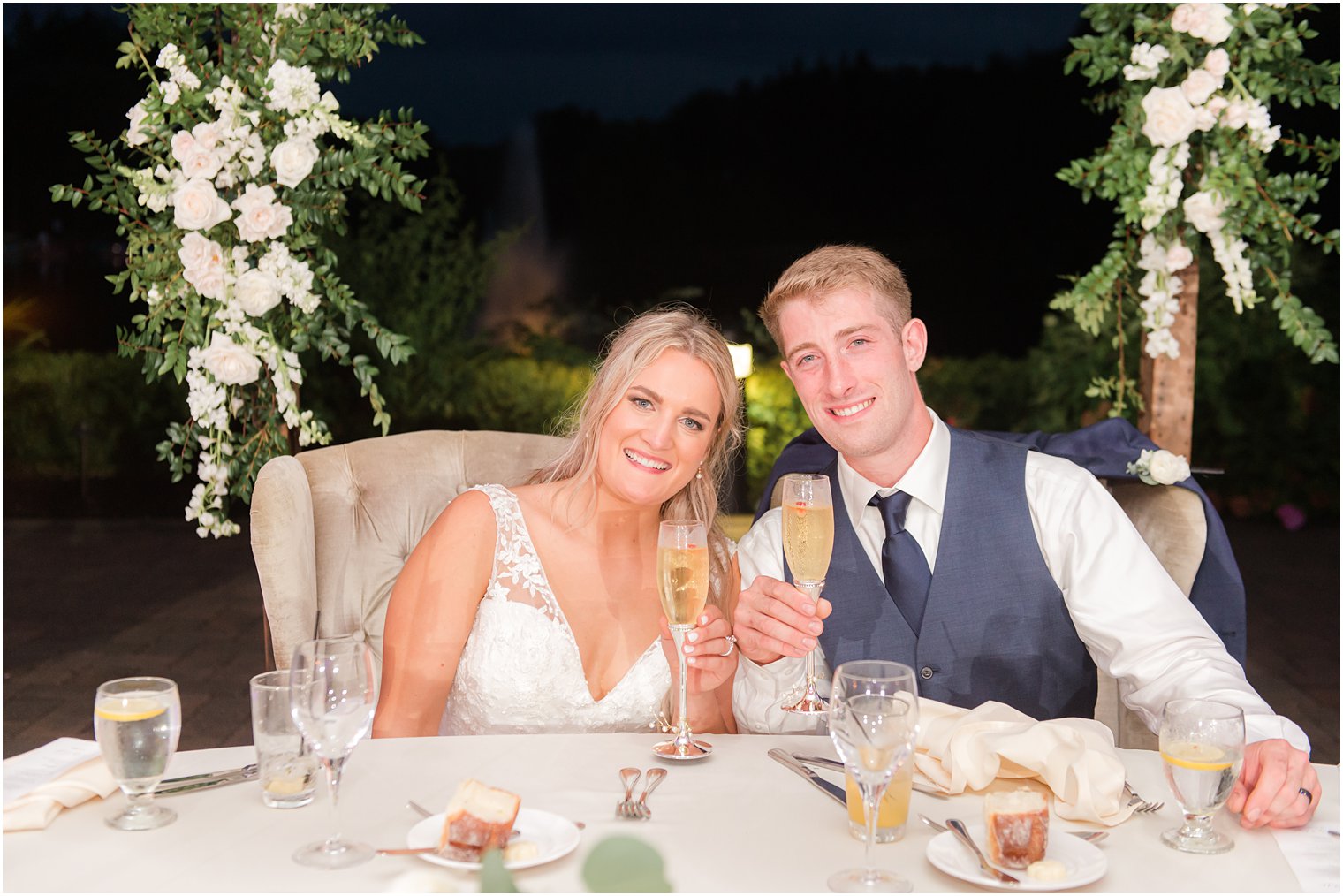 bride and groom lean heads together sitting at sweetheart table 