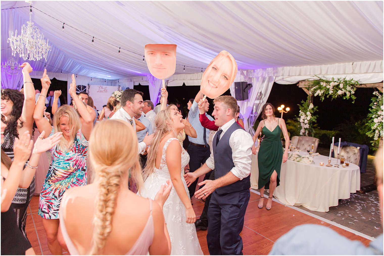 bride and groom dance with guests with paper cutouts of their heads 