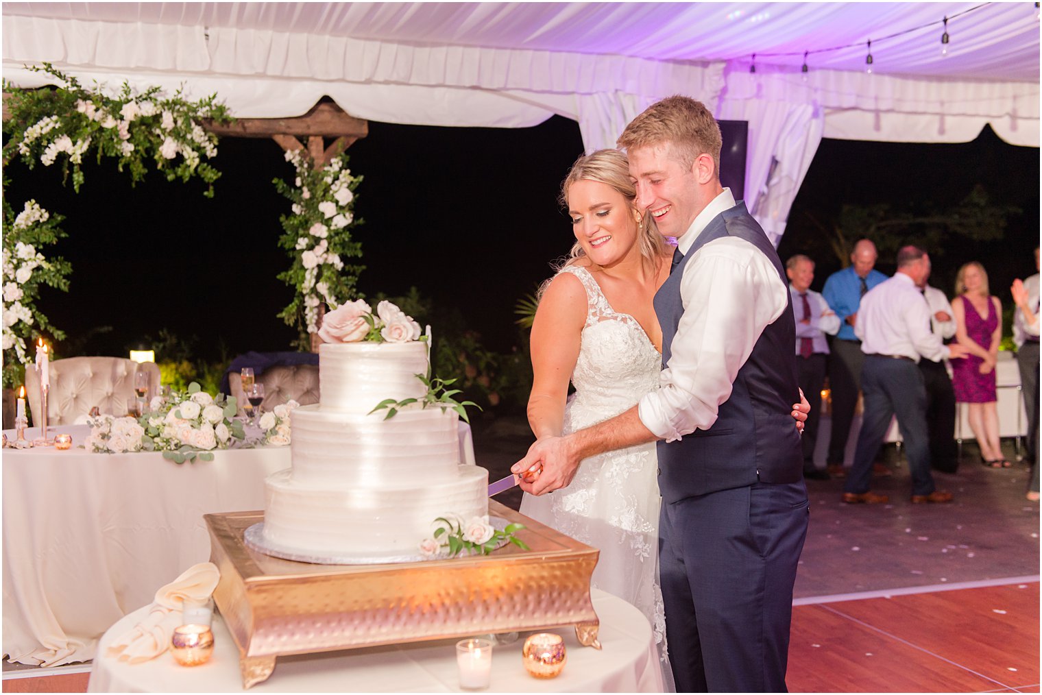 bride and groom cut wedding cake under tent at Windows on the Water at Frogbridge