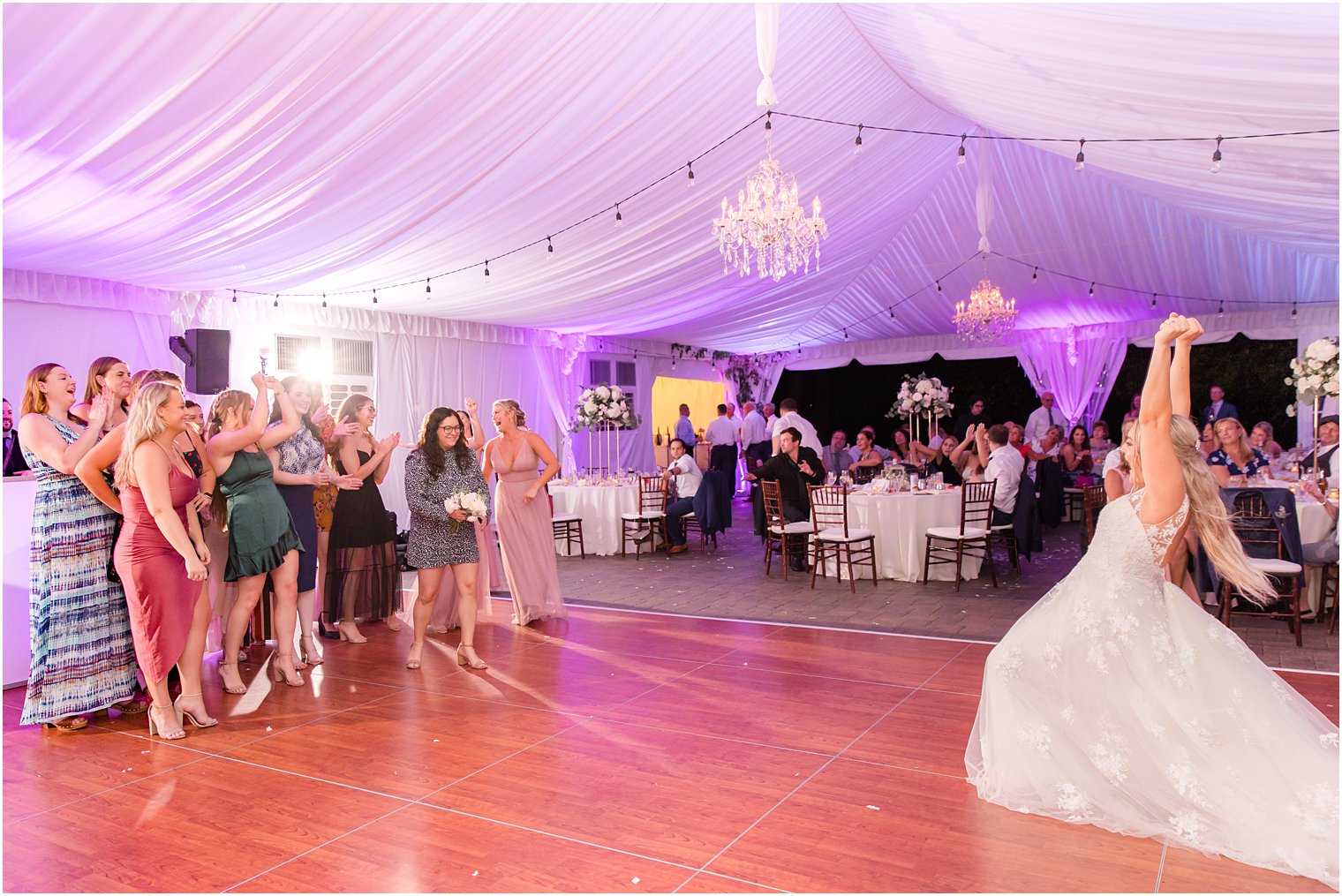 bride tosses bouquet and cheers with guests during reception 