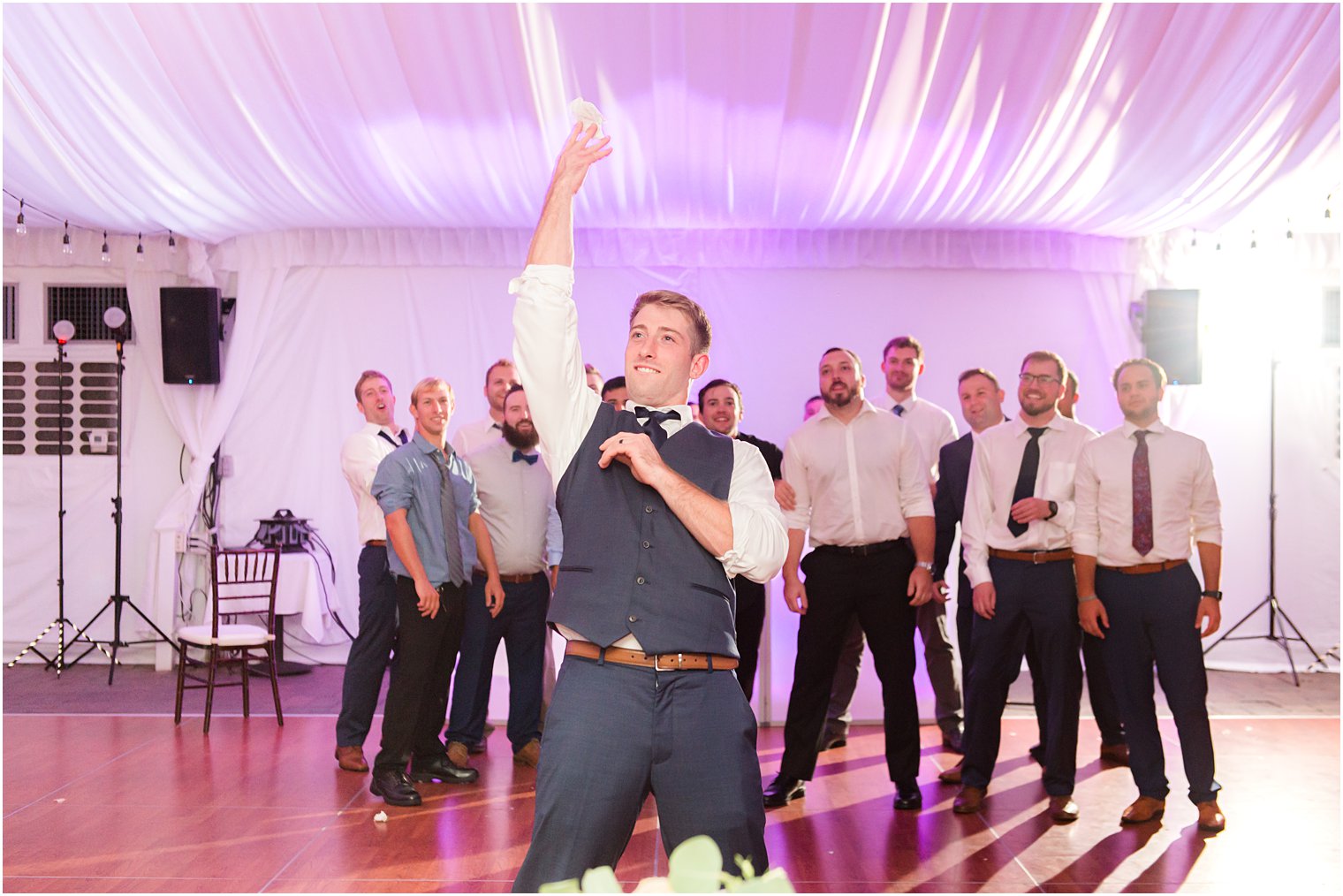 groom tosses garter to male guests 