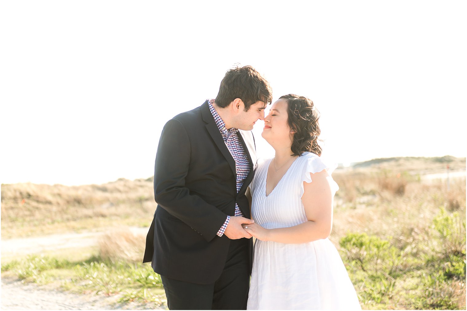 groom leans down to kiss bride during portraits on Avalon NJ beach