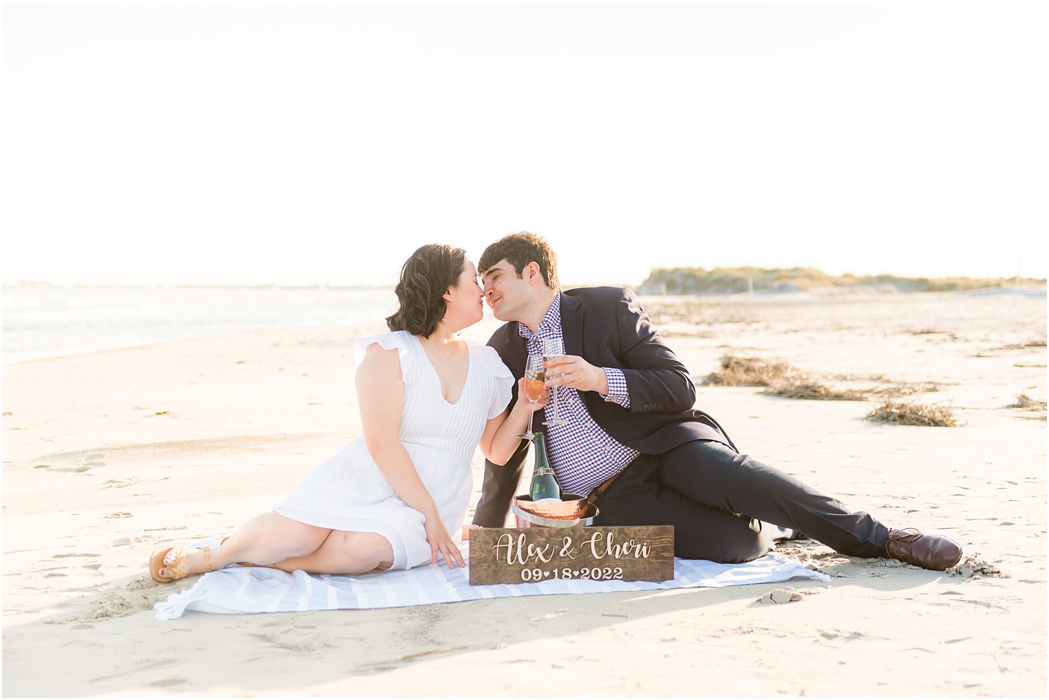 engaged couple toasts with champagne on blanket on Avalon NJ beach