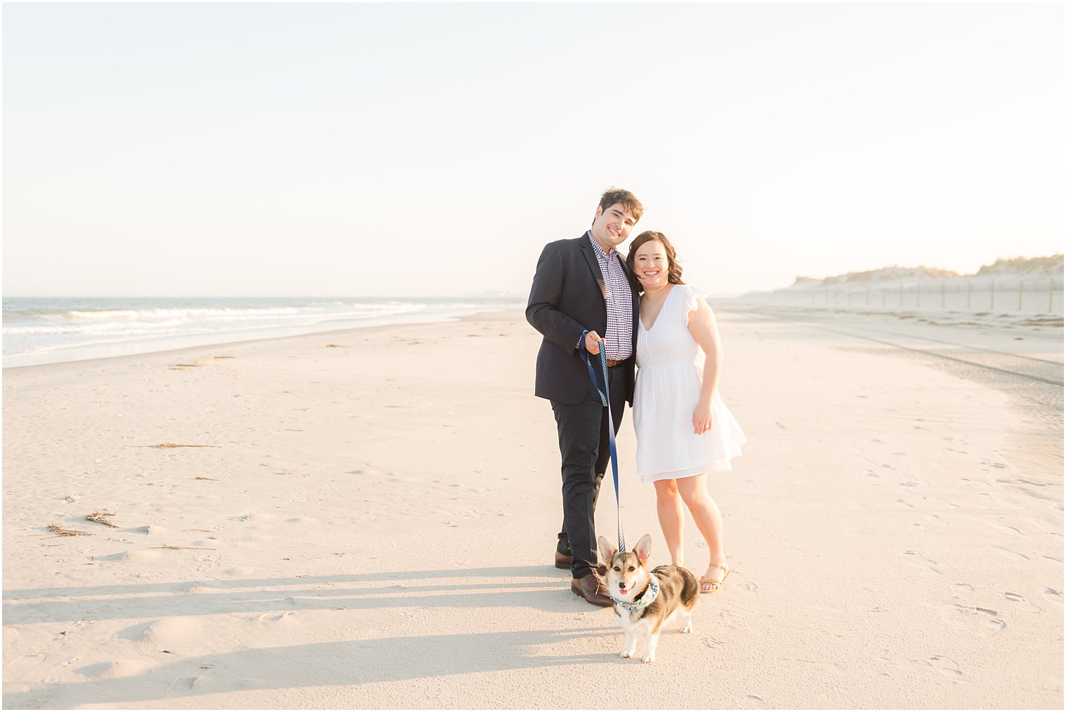 engage couple walks dog on beach during engagement session in Avalon NJ