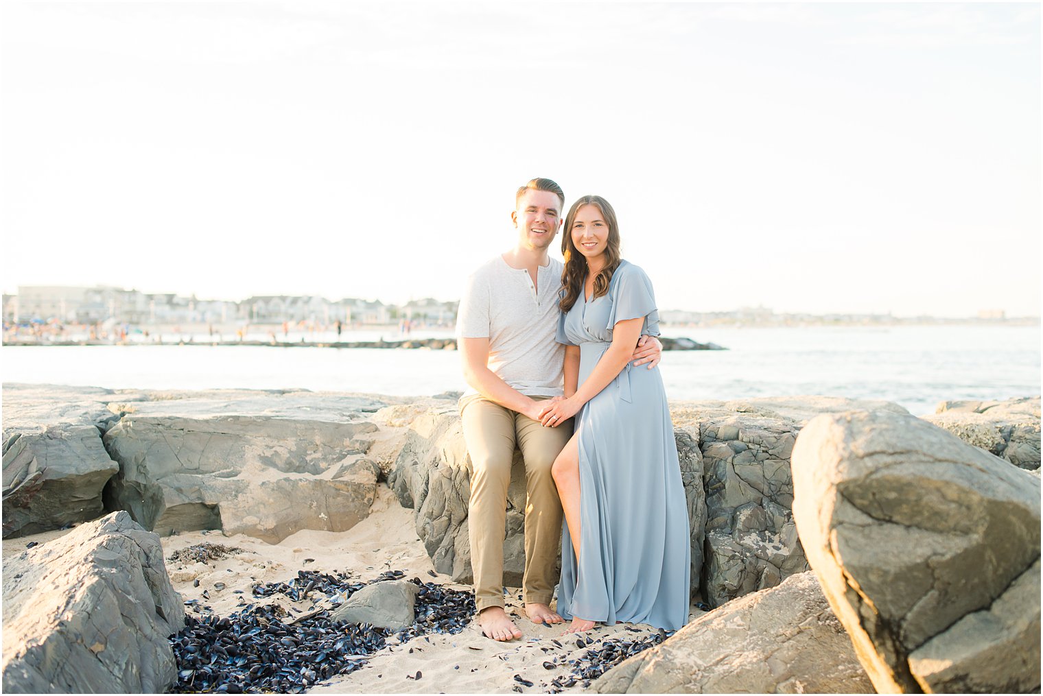 engaged couple sits together on rocks on the Jersey Shore