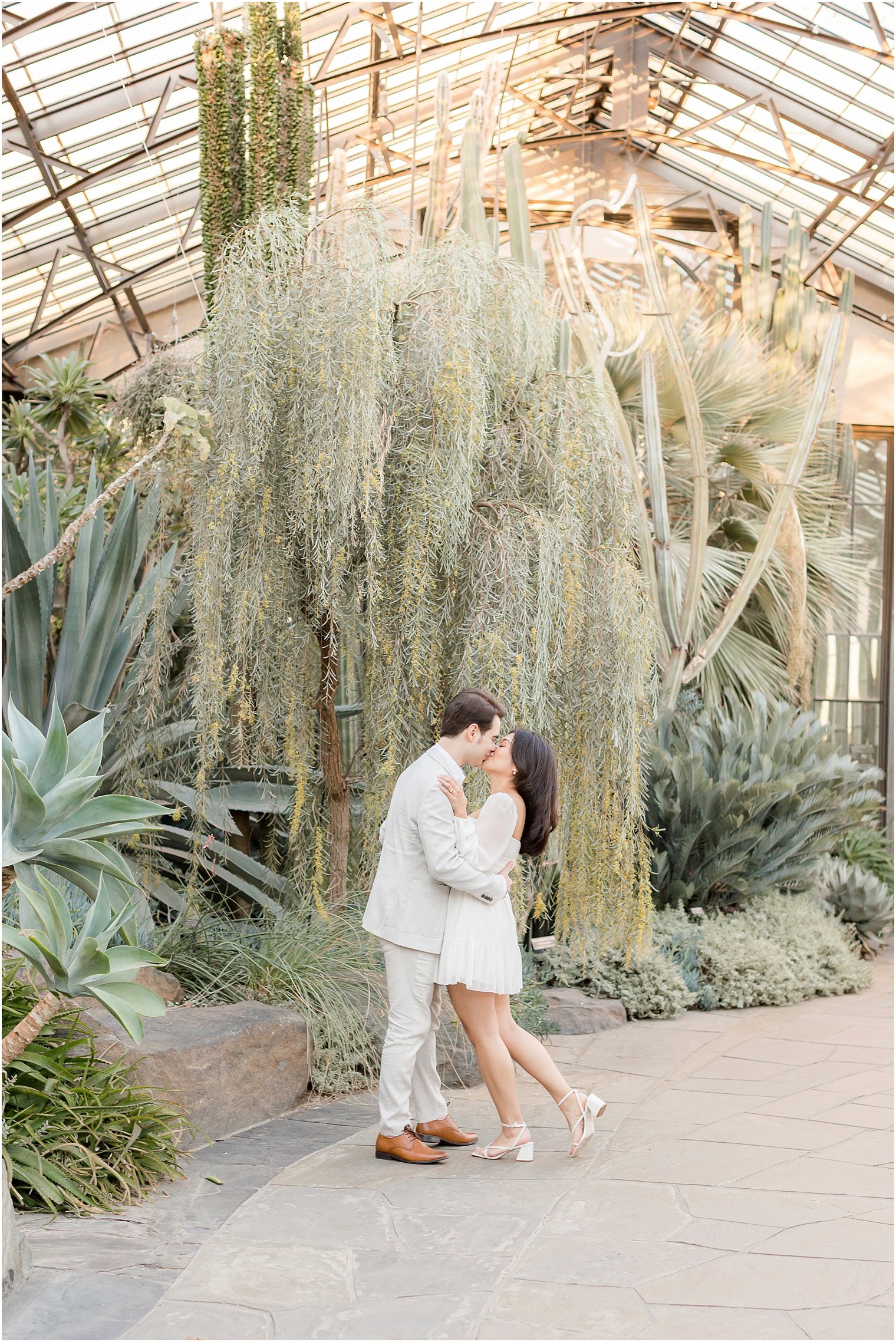bride and groom hug in front of weeping willow inside Longwood Gardens