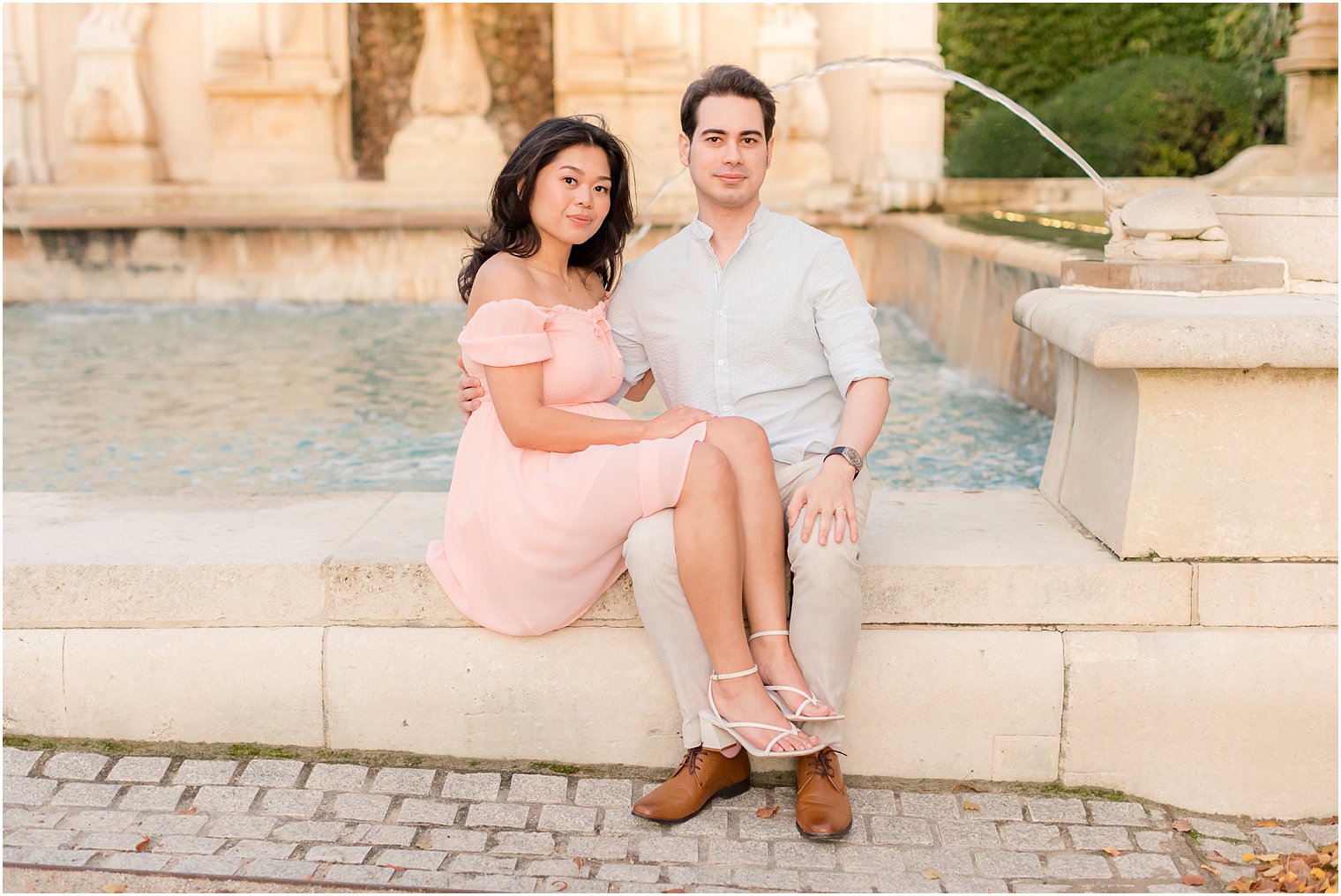 bride and groom sit together by fountain at Longwood Gardens