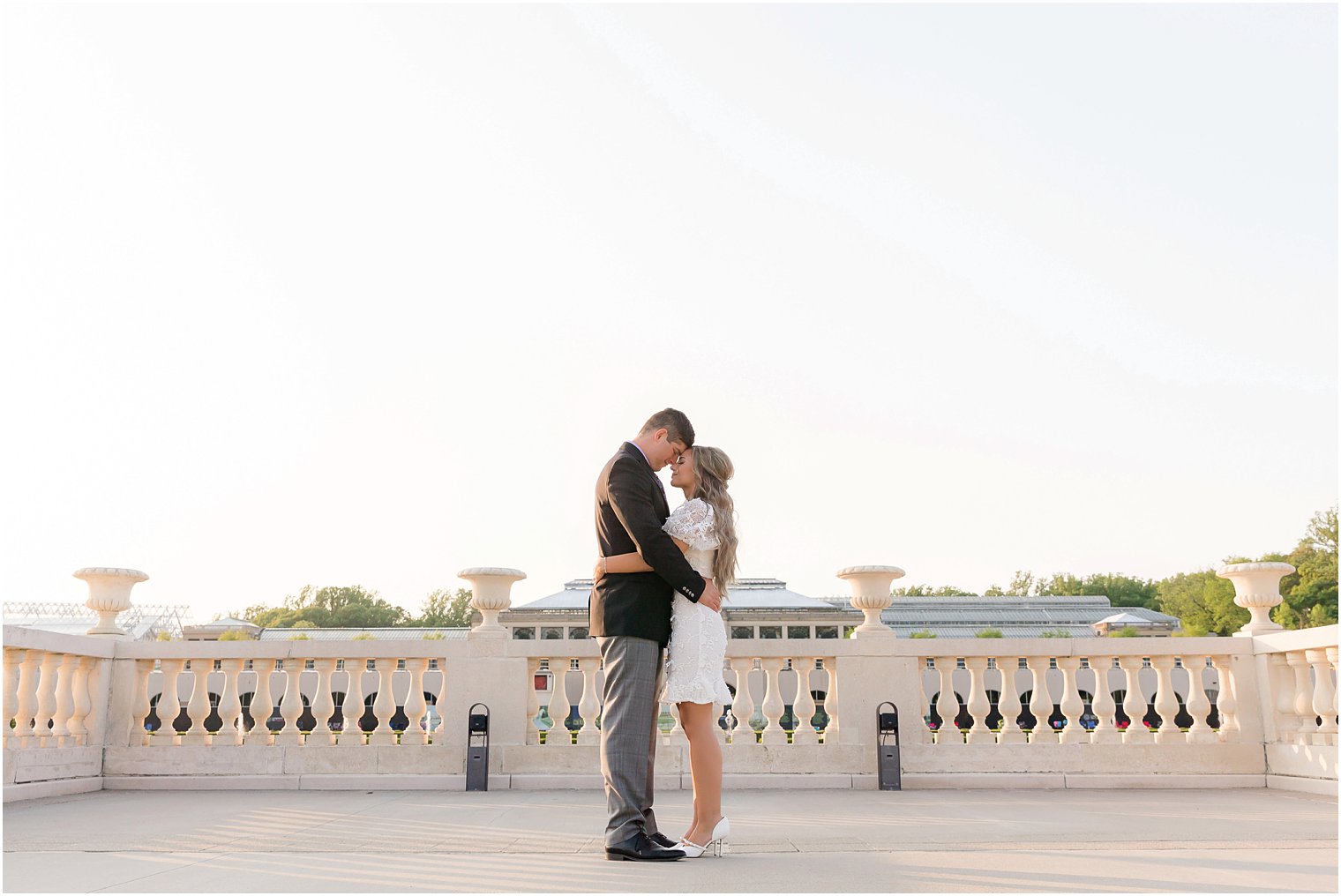 bride and groom hug on top of Longwood Gardens during engagement session