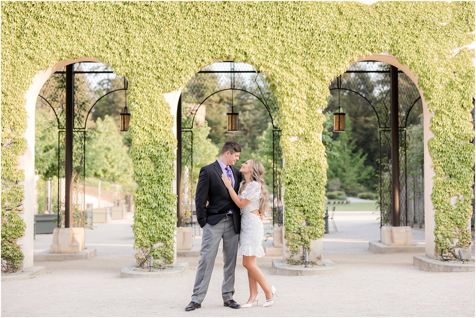 bride and groom hug in front of greenery covered wall at Longwood Gardens