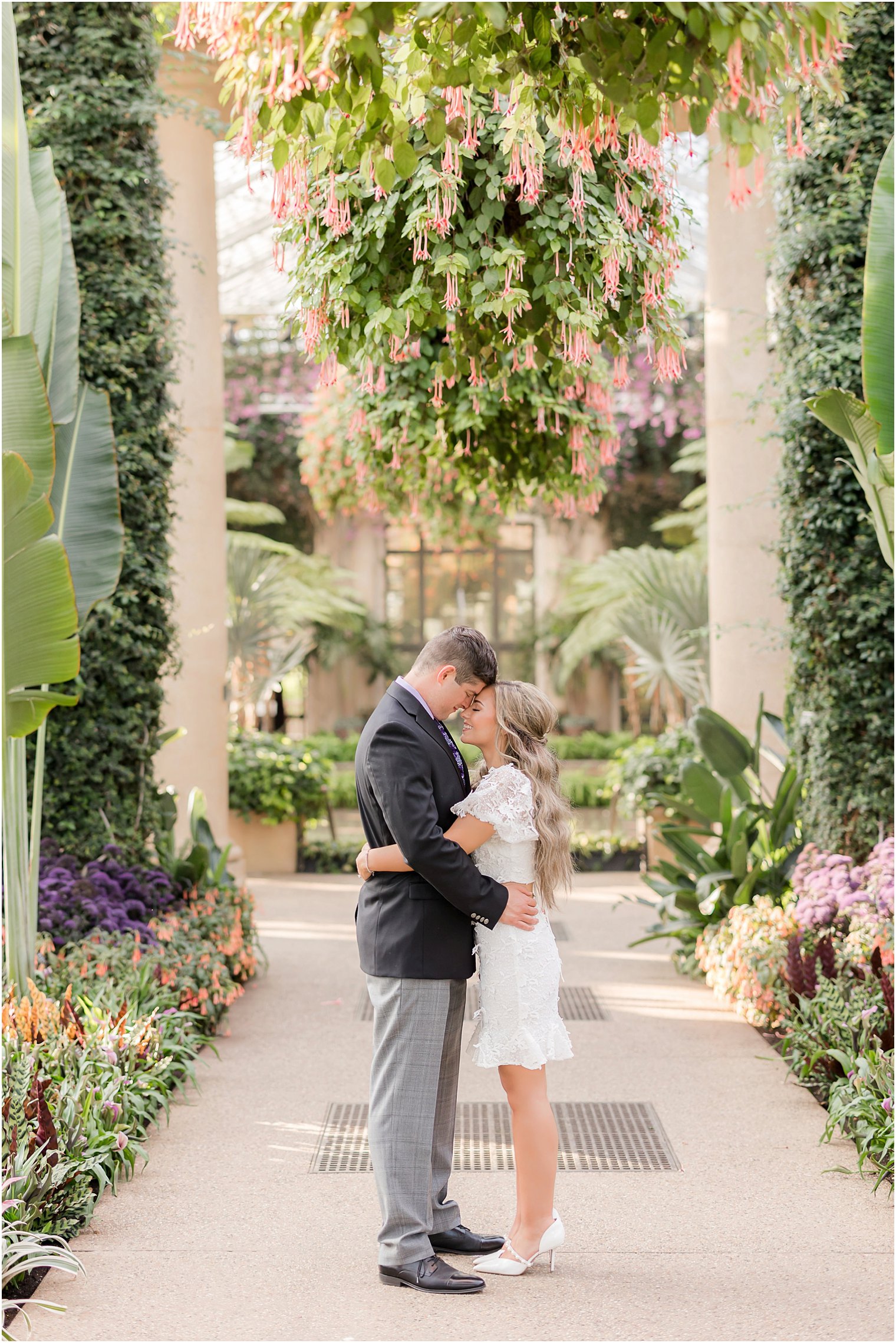 bride and groom stand in hanging gardens during Longwood Gardens engagement session