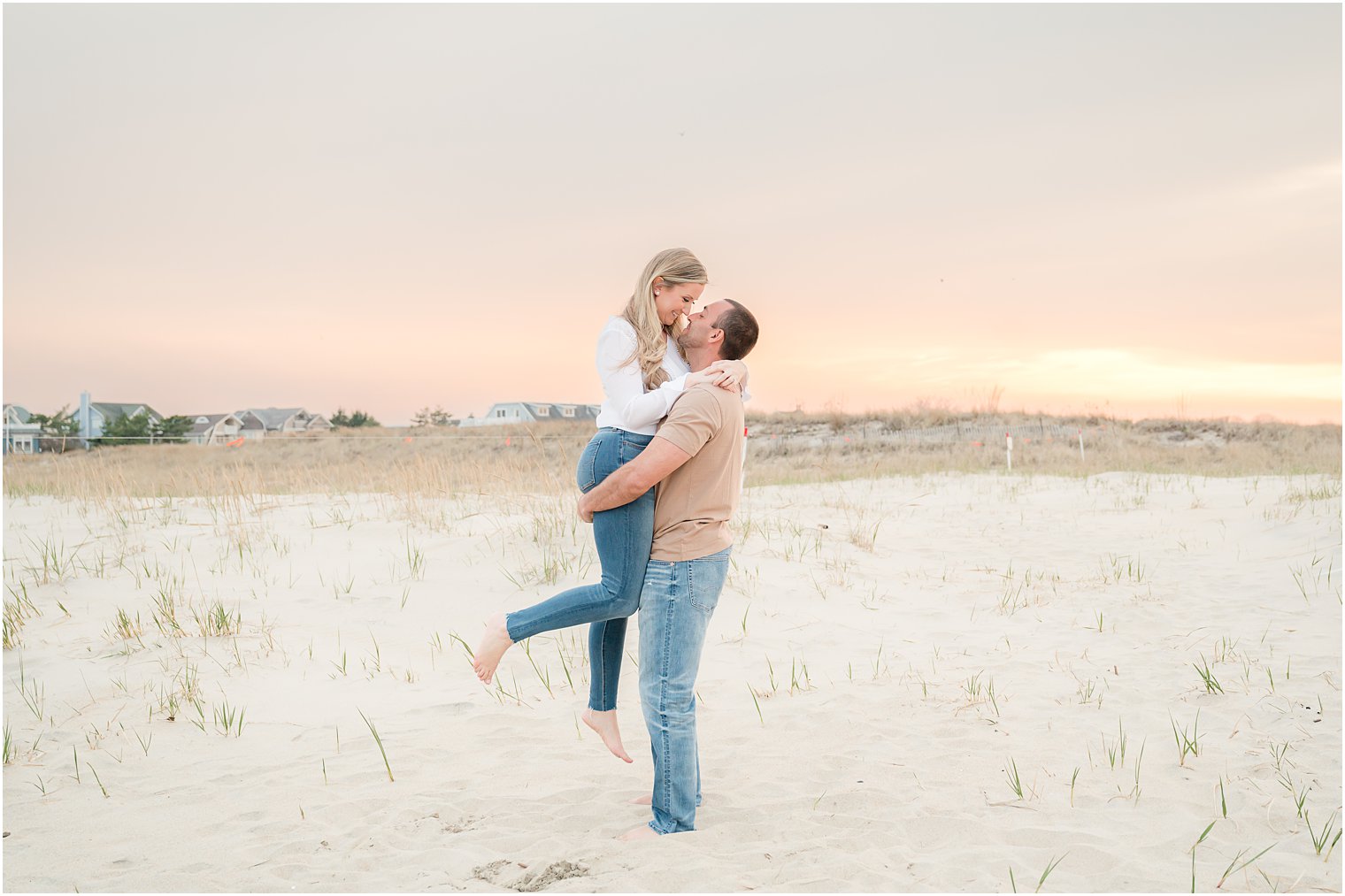 groom lifts bride up at sunset during Spring Lake engagement session at Spring Lake Beach