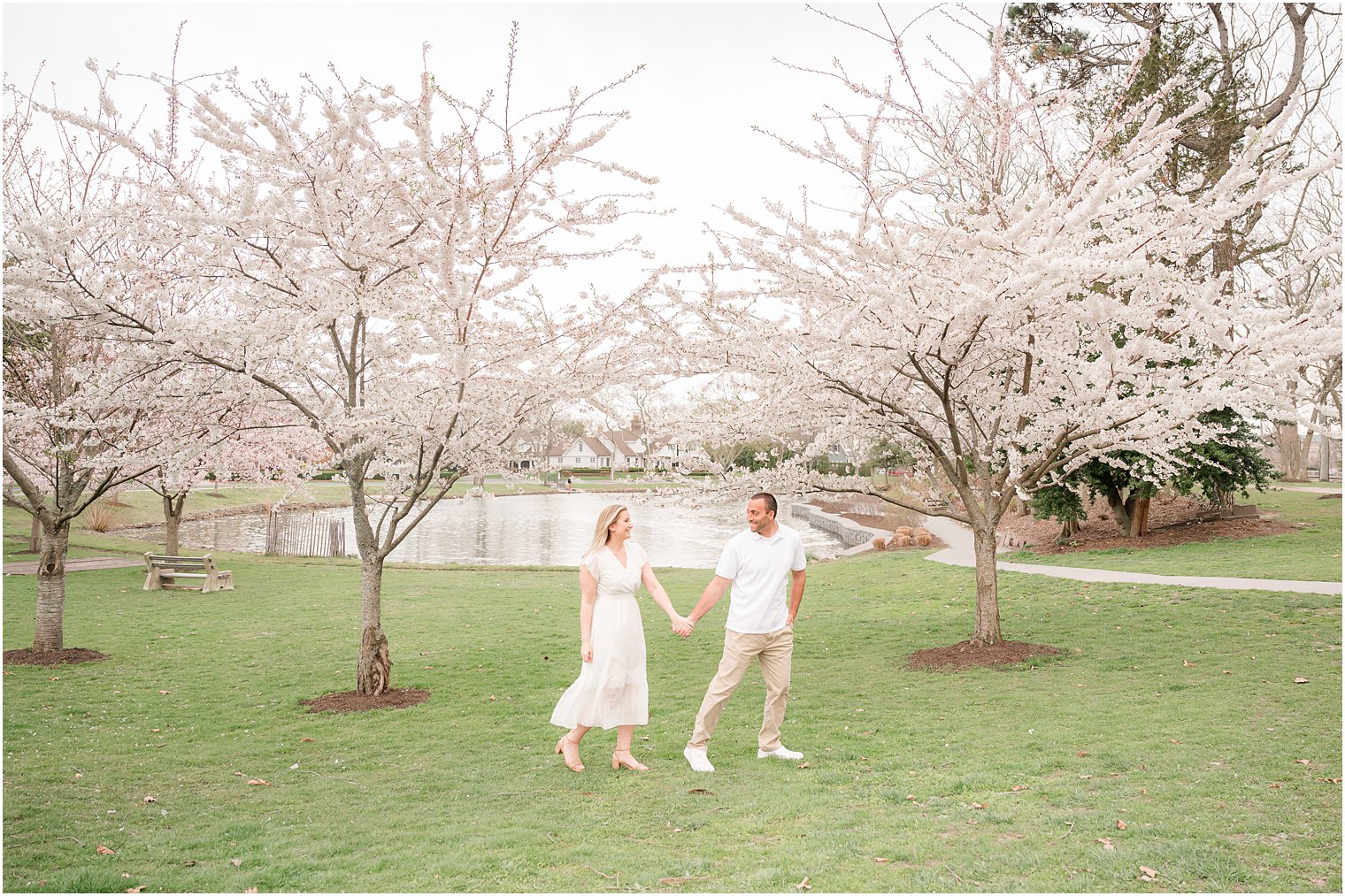 engaged couple holds hands walking through Divine Park during Spring Lake engagement session