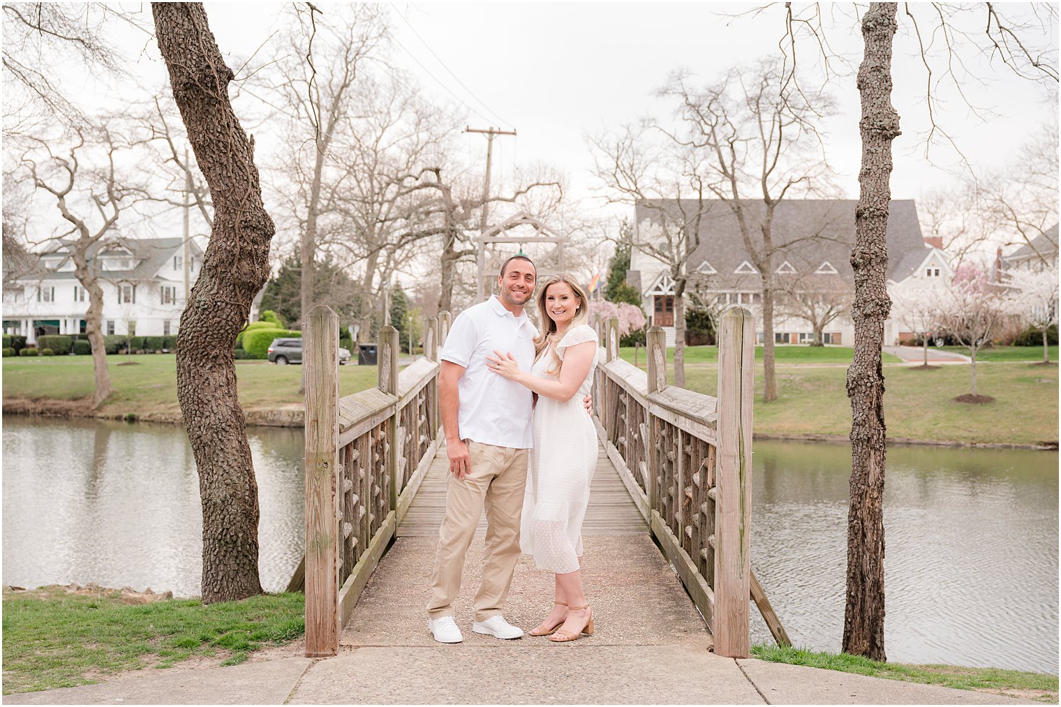 bride and groom stand on wooden bridge in Divine Park during Spring Lake engagement session