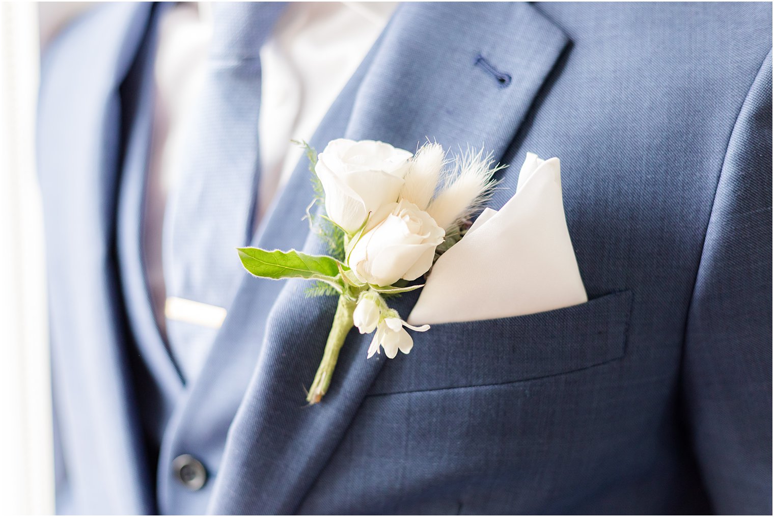 groom's navy suit with ivory boutineere and pocket square