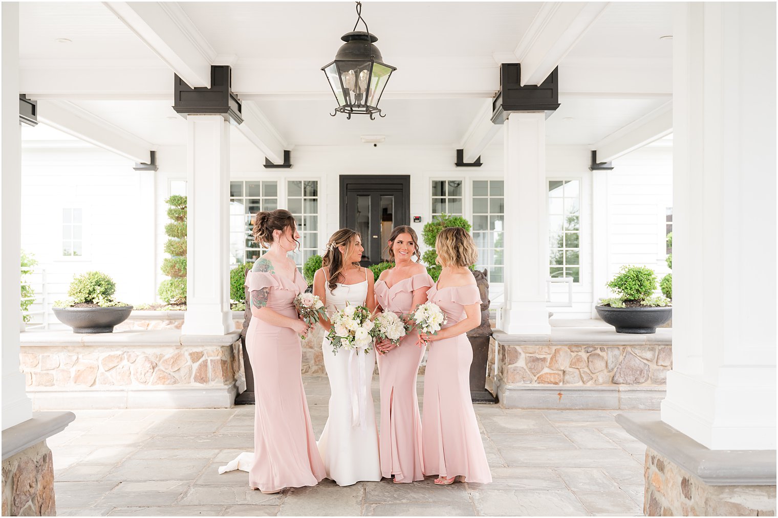 bride smiles with bridesmaids in pale pink gowns at Ryland Inn
