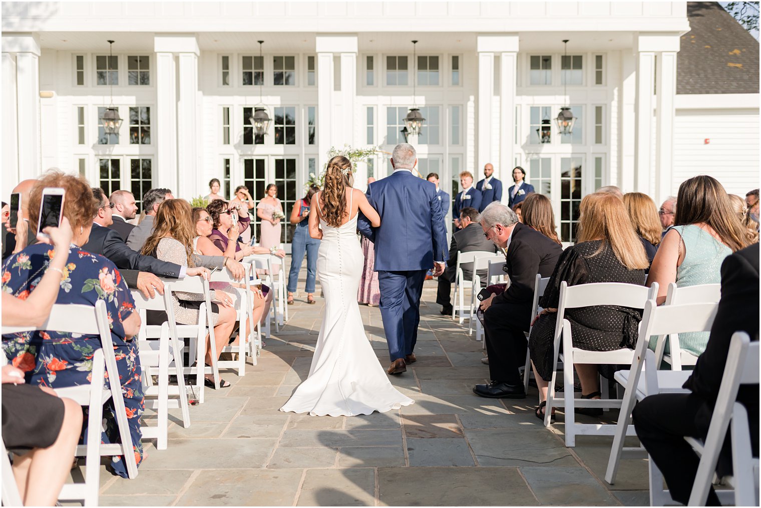 bride and dad walk down aisle for ceremony on patio at Ryland Inn
