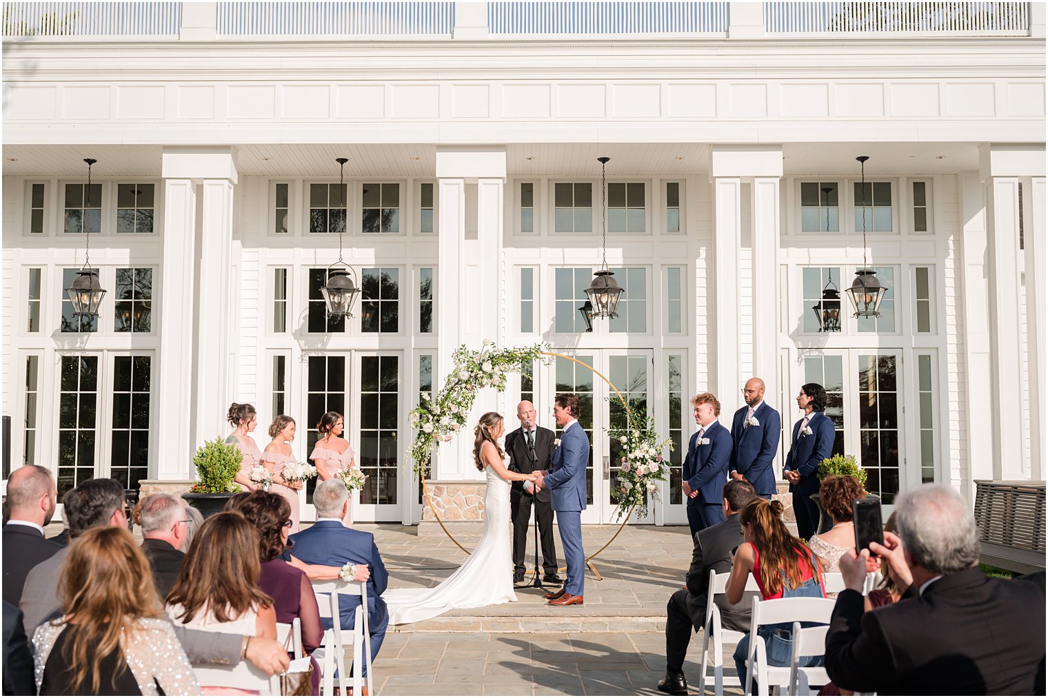 bride and groom hold hands during ceremony on patio at Ryland Inn