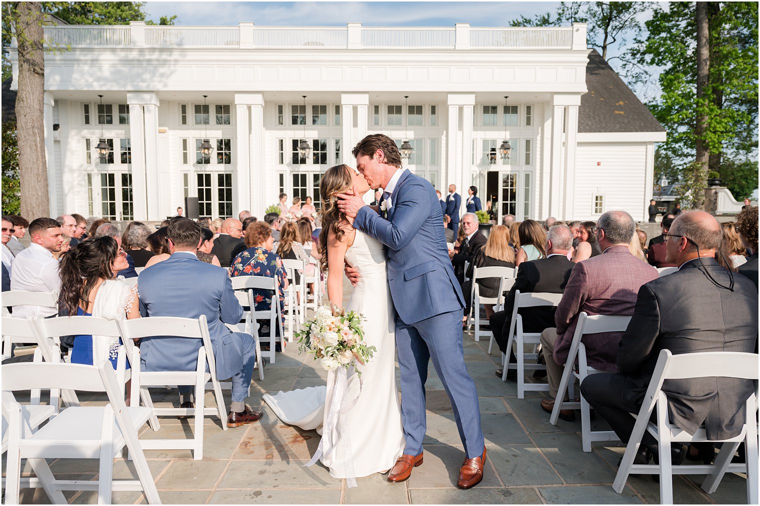 newlyweds kiss in aisle after ceremony on patio at Ryland Inn