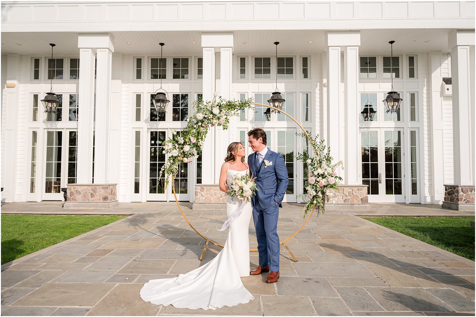 bride and groom stand in front of arbor on patio at Ryland Inn