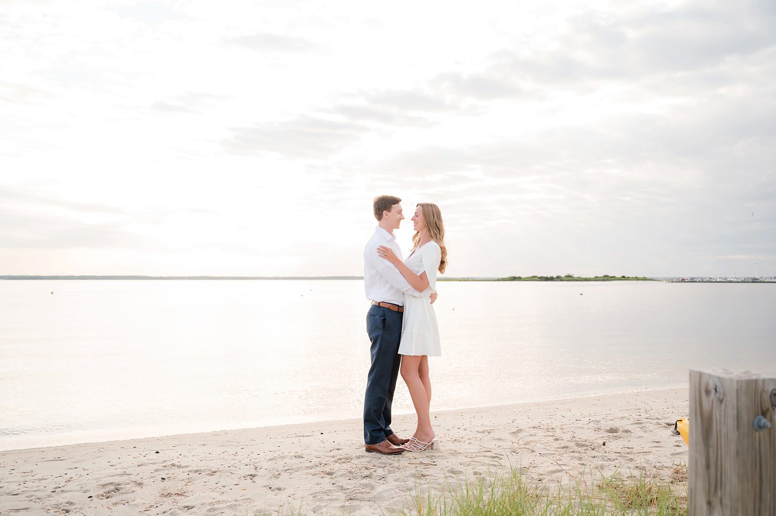 Engaged couple looking each other with a beautiful sunset as backdrop at Lavalette NJ