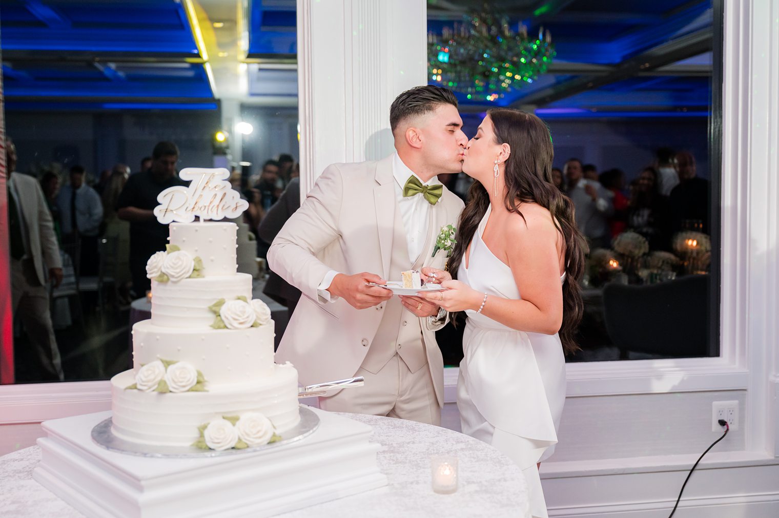 couple kissing while cutting their wedding cake at The Mill Lakeside Manor