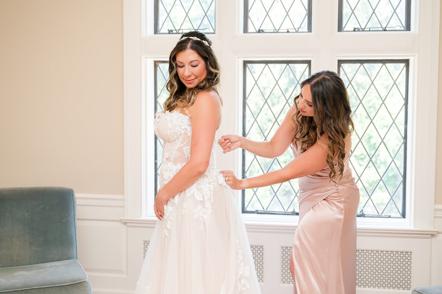 Bridesmaid helping the bride in her big day to get ready at Riverhouse at Rumson Country Club