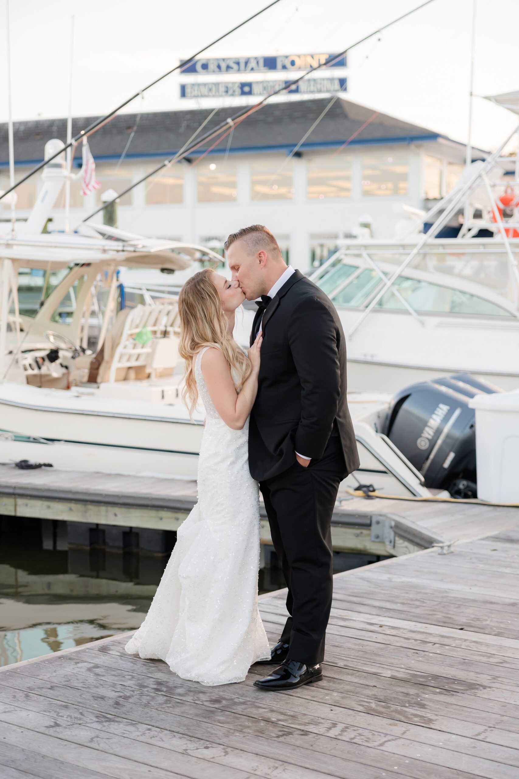 Bride and groom sharing a kiss with boats in the background