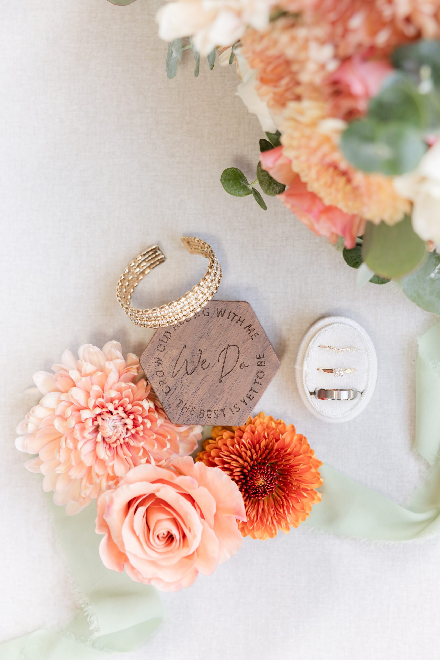 Wedding rings rest delicately among soft peach and blush florals, capturing a romantic symbol of love and commitment