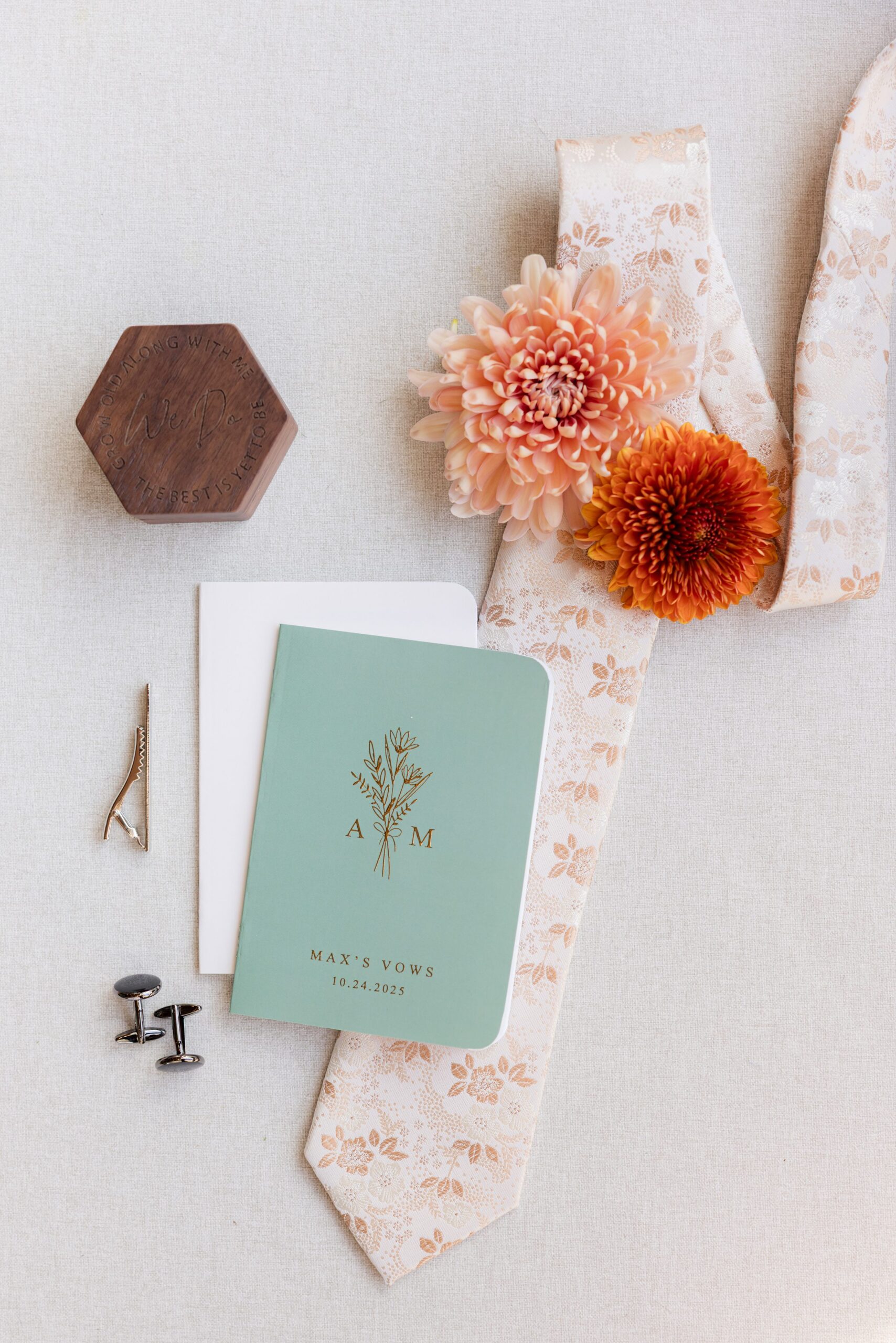 Delicate florals, refined cufflinks, and a patterned tie are thoughtfully arranged, reflecting a day rooted
