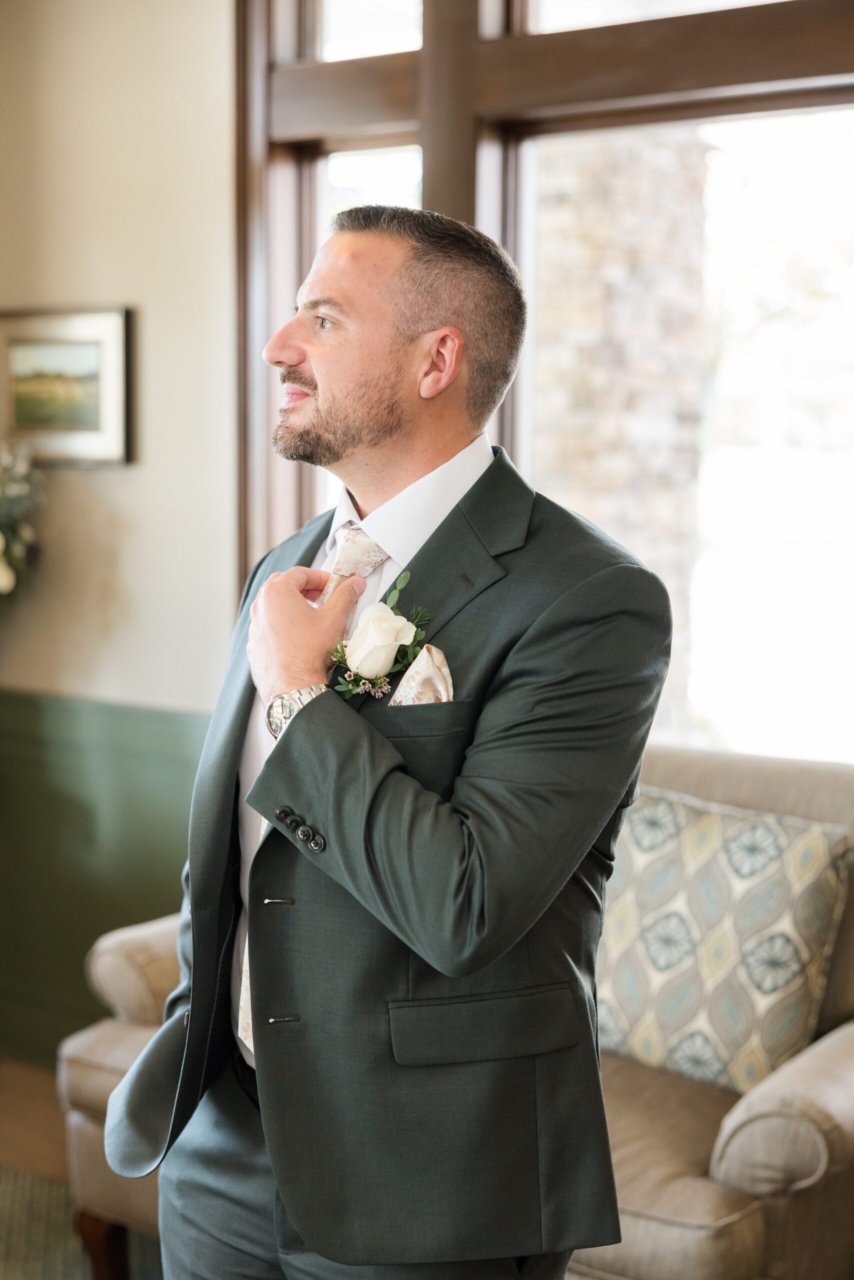 Groom stands by the window, reflecting quietly before seeing his bride