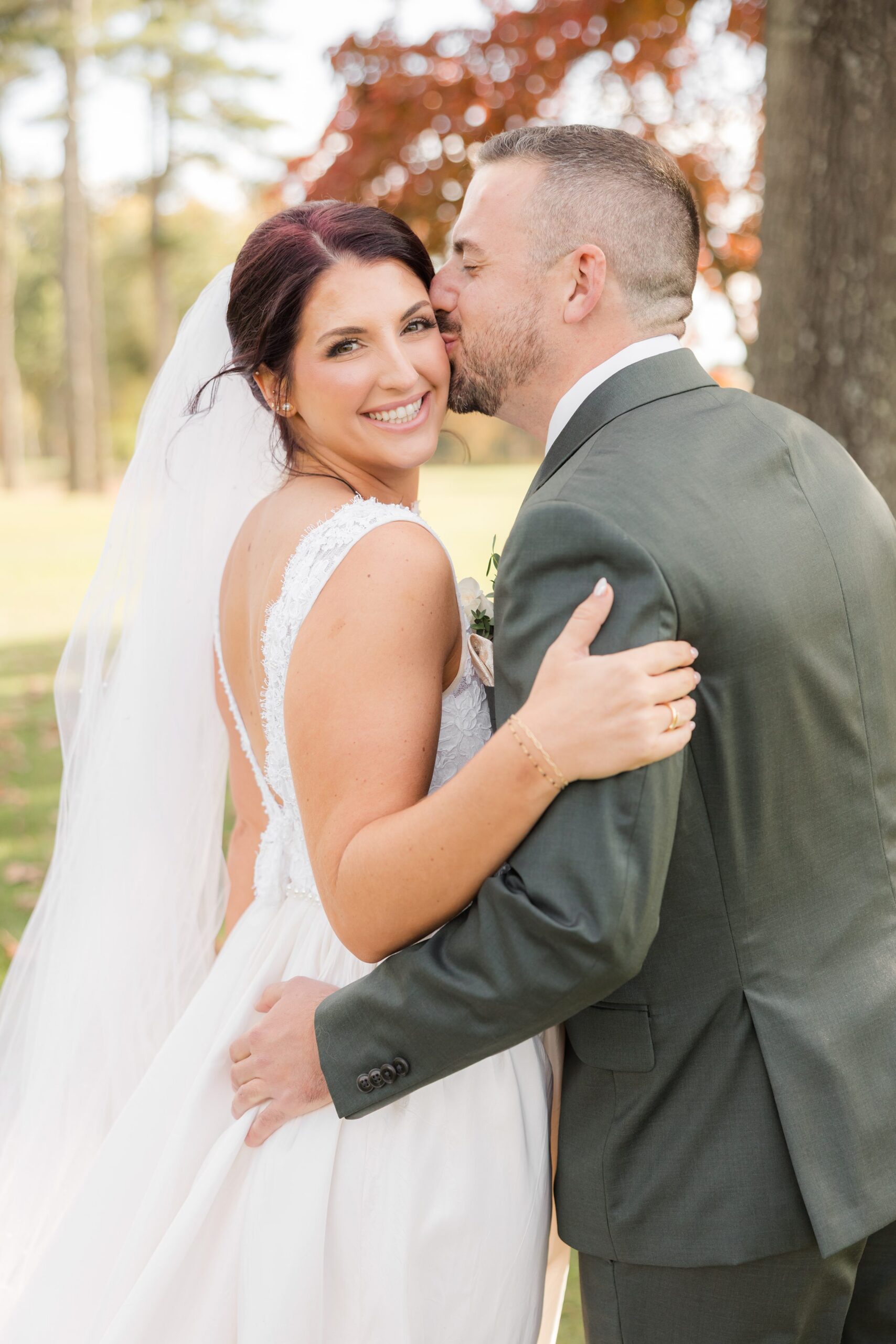 Groom kisses the bride’s cheek as she smiles radiantly, wrapped in a moment of pure affection